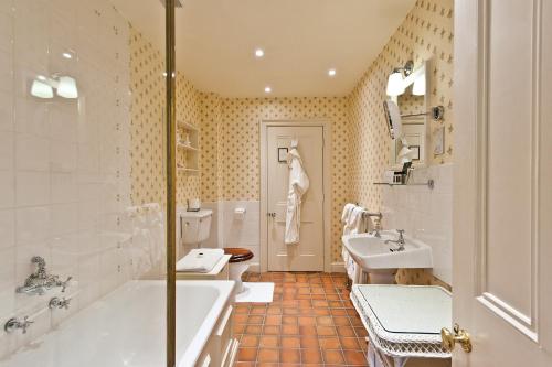 a bathroom with two sinks and a tub and a toilet at Bodysgallen Hall and Spa in Llandudno