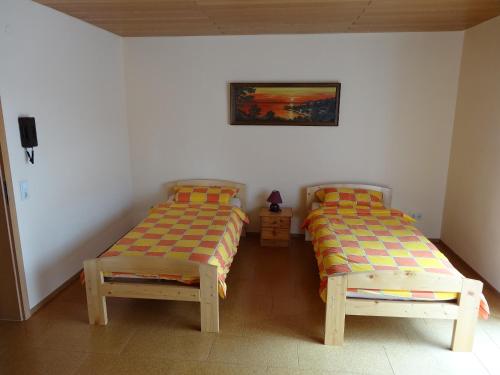 Un dormitorio con 2 camas y una silla. en Lembergblick, en Wellendingen