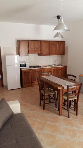 una cucina con tavolo in legno e una cucina con frigorifero bianco di Casa Vacanze Nonna Defenza a Teulada