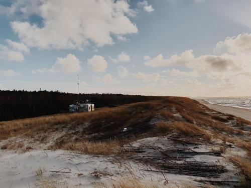 a beach with a house in the sand and the ocean at Amber Ambient Apartments in Juodkrantė