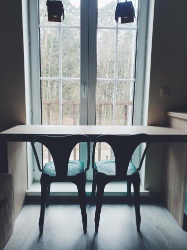 a table with two chairs in front of a window at Amber Ambient Apartments in Juodkrantė