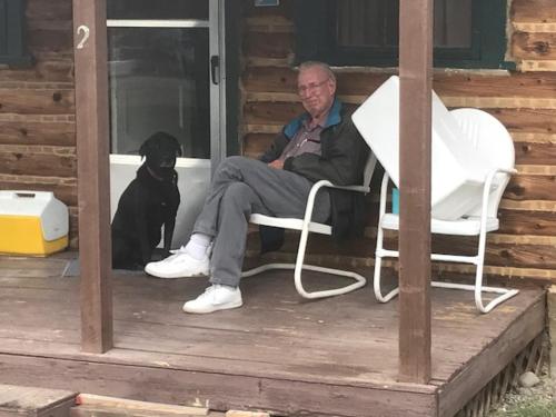 a man sitting in a chair with a dog on a porch at Grandview Cabins & RV Resort in South Fork