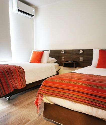 a hotel room with two beds with red pillows at Apart Hotel Viva Providencia in Santiago