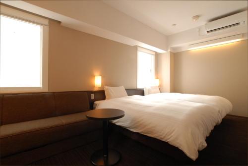 a bedroom with a bed and a couch and a window at AB Hotel Nagoya Sakae in Nagoya