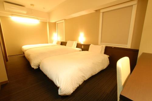 two beds in a hotel room with white sheets at AB Hotel Nagoya Sakae in Nagoya