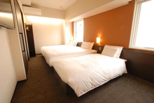 a hotel room with two beds and a window at AB Hotel Toyohashi in Toyohashi