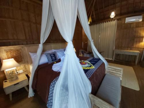 a bedroom with a bed with a mosquito net at Kirani Joglo Villa Bali by Mahaputra in Sukawati