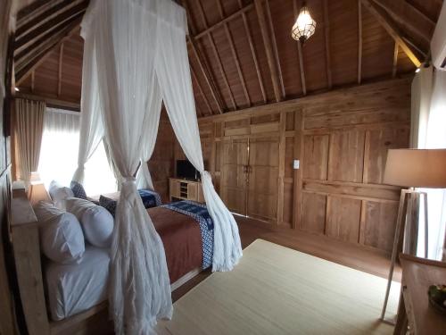 a bedroom with a bed with a mosquito net at Kirani Joglo Villa Bali by Mahaputra in Sukawati