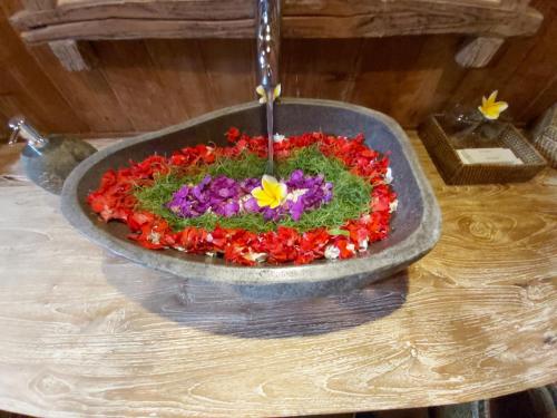a water fountain with flowers in a bowl on a table at Kirani Joglo Villa Bali by Mahaputra in Sukawati