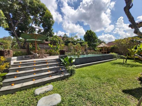 a garden with a bench and a swimming pool at Kirani Joglo Villa Bali by Mahaputra in Sukawati