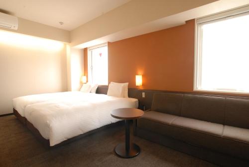a bedroom with a bed and a couch and a window at AB Hotel Toyohashi in Toyohashi