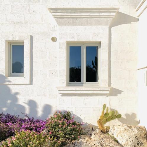 a white brick house with two windows and flowers at Masseria San Francesco in Savelletri di Fasano