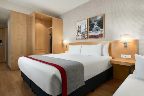 ein Hotelzimmer mit einem großen Bett und einem Stuhl in der Unterkunft Ramada by Wyndham Madrid Getafe in Getafe