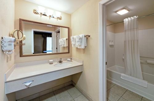a bathroom with a sink and a mirror and a shower at staySky Suites I-Drive Orlando Near Universal in Orlando