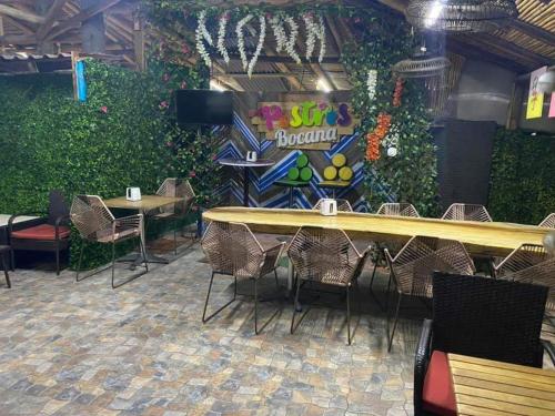 um restaurante com mesas e cadeiras e uma parede de plantas em Costa Miramar em Acapulco