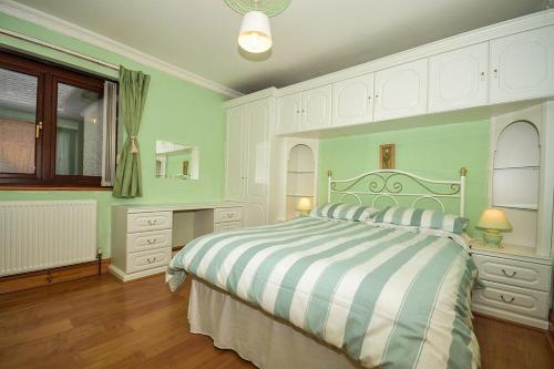 1 dormitorio con 1 cama grande con manta a rayas en Simdde Wen en Beaumaris