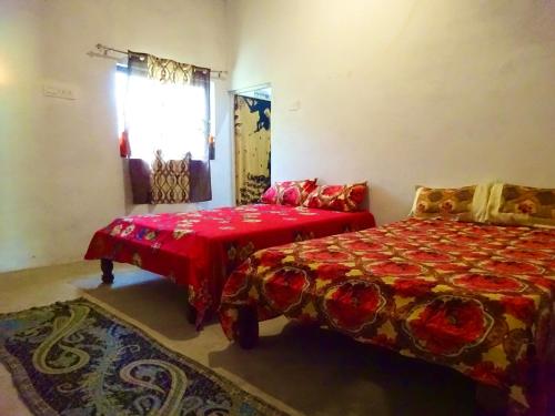 a bedroom with a bed and a red blanket at Maji Homestay Khajuraho in Khajurāho