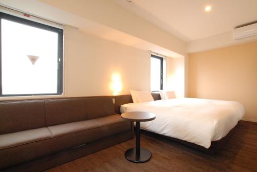 a bedroom with a bed and a couch and a window at AB Hotel Isesaki in Isesaki