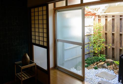 una puerta de cristal que conduce a un jardín exterior en Shiki Homes HIKARI en Kioto
