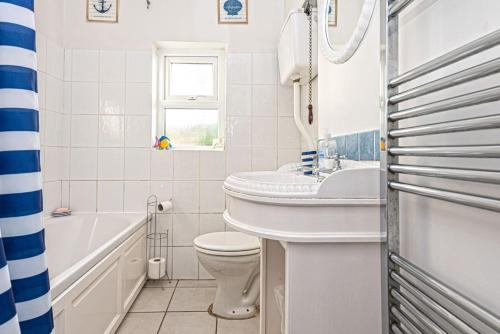 a bathroom with a sink and a toilet and a tub at The Moorings in Cemaes Bay