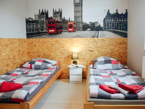 two beds in a room with a picture of big ben at Bielik - Pokoje Gościnne in Płock