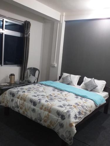 a bedroom with a bed and a table and a window at Madys view -Aaple Ghar in Darjeeling