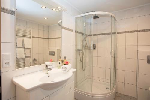 a white bathroom with a sink and a shower at Hotel Lindenhof in Meschede