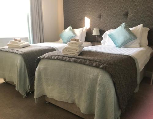 two beds in a hotel room with towels on them at Woodsome Hall Golf Club Cottage on the Course in Fenay Bridge