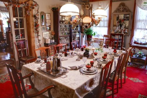 uma sala de jantar com uma mesa longa e cadeiras em The Queen, A Victorian Bed & Breakfast em Bellefonte