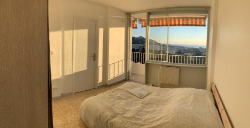 um quarto com uma cama e uma grande janela em Boost Your Immo Marseille La Rouvière 121E1 em Marselha