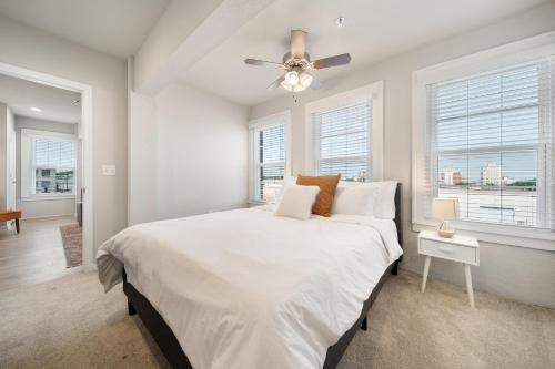 a white bedroom with a bed and a ceiling fan at Stunning Waco Downtown Apartments in Waco