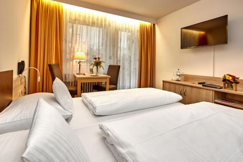 バートライヘンハルにあるホテル バイエルン ヴィタルのベッド2台とデスクが備わるホテルルームです。