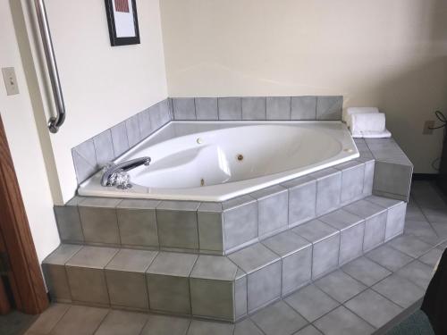 a white bath tub sitting on top of a tiled floor at AmericInn by Wyndham Blackduck in Blackduck