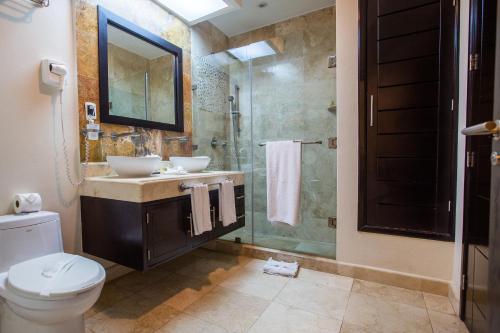 a bathroom with a toilet and a sink and a shower at El Faro 301 Coral in Playa del Carmen