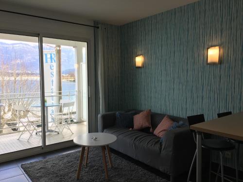 a living room with a couch and a table and a balcony at Vue sublime sur le lac du Bourget in Le Bourget-du-Lac