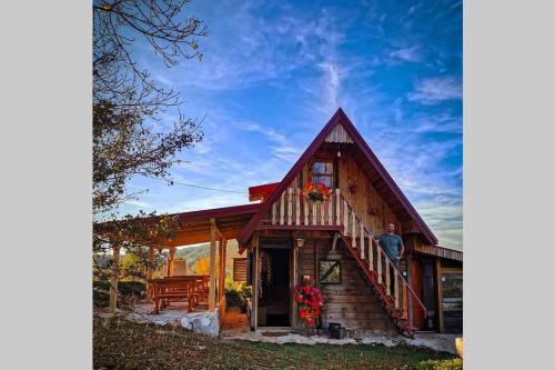 a man standing on the porch of a log house at Log cabin Uvac (Vikendica Saponjic) in Nova Varoš