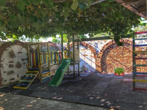 a playground with a green slide in a brick wall at Motel Kiwi in Grude