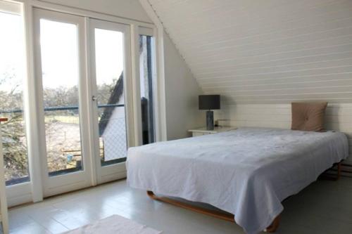a bedroom with a bed and a large window at Stråtækt idyl i skoven in Fredensborg