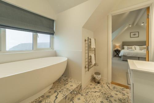 a bathroom with a bath tub and a bedroom at Westaway in Portreath