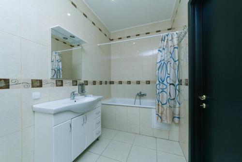 W łazience znajduje się umywalka, wanna i lustro. w obiekcie Mango w Kijowie