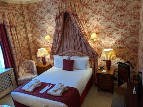 a hotel room with a bed with two towels on it at Cotswold Lodge Hotel in Oxford