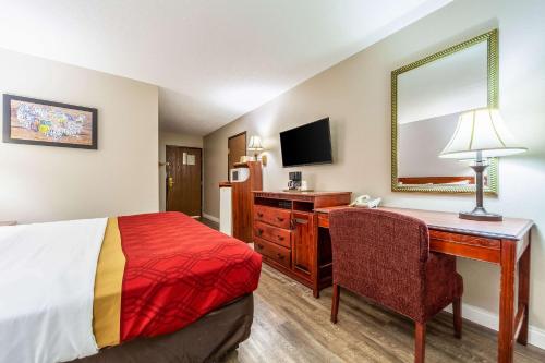 a hotel room with a bed and a desk and a mirror at Econo Lodge Lincoln in Lincoln