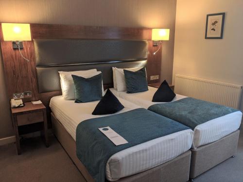 a hotel room with two beds and a headboard at Cotswold Lodge Hotel in Oxford