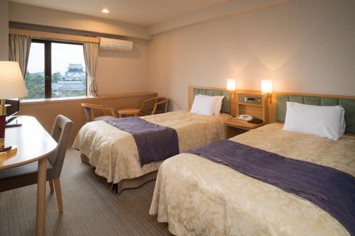 a hotel room with two beds and a table at Okazaki New Grand Hotel in Okazaki