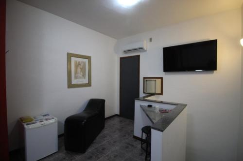 um quarto de hotel com uma cadeira e uma televisão na parede em Motel Strattus (Adults Only) em Belo Horizonte