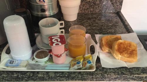 a tray with breakfast foods and drinks on a counter at Motel Strattus (Adults Only) in Belo Horizonte