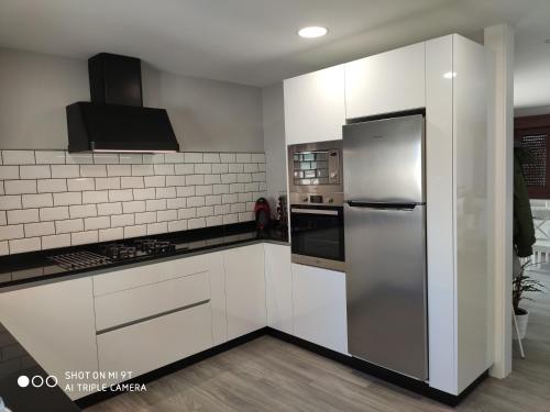 uma cozinha com armários brancos e um frigorífico de aço inoxidável em Mareventus em Sanxenxo