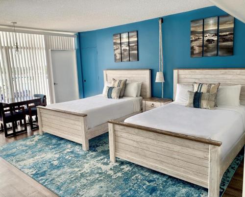 two beds in a bedroom with blue walls at Sands Harbor Resort and Marina in Pompano Beach