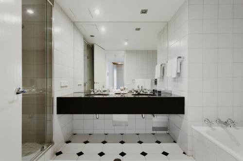 a bathroom with a shower and a sink and a tub at Mercure Melbourne Albert Park in Melbourne