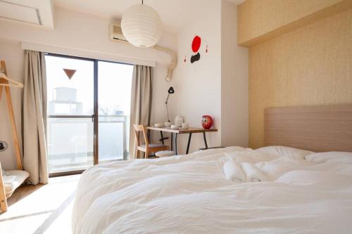 a bedroom with a white bed with a window and a table at Dwell Urban 6C in Tokyo